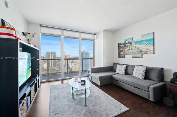 a living room with furniture a flat screen tv and a floor to ceiling window