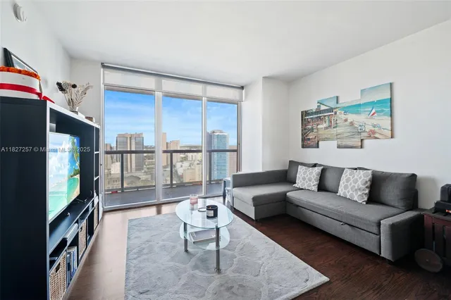 a living room with furniture a flat screen tv and a floor to ceiling window