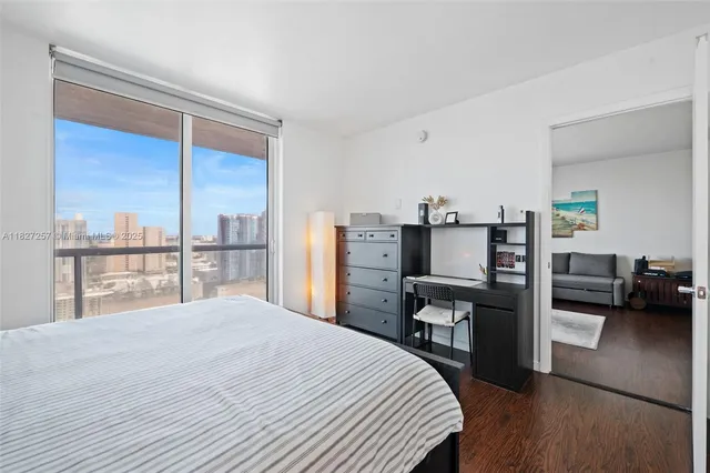 a bedroom with a bed a large window and dresser