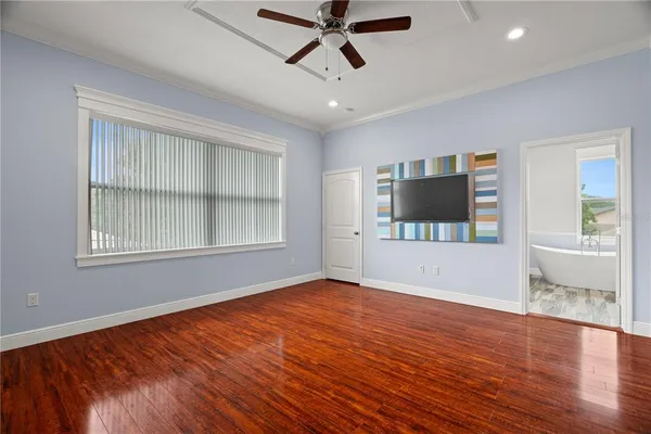 a view of empty room with wooden floor and fan