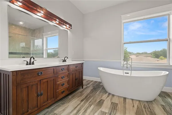 a spacious bathroom with a double vanity sink a mirror and a bathtub