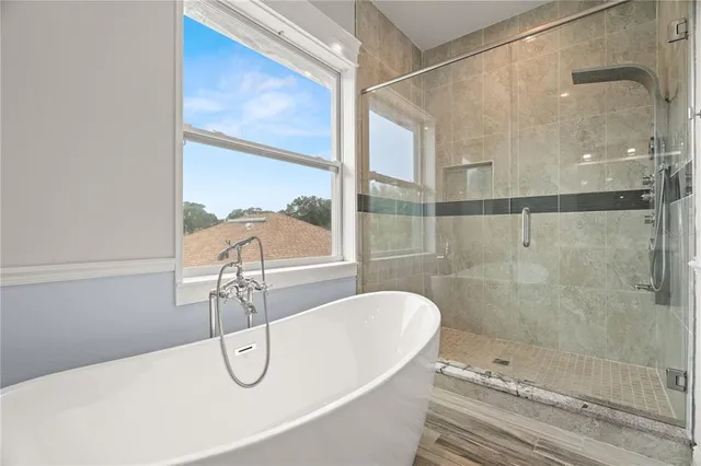 a bathroom with a white bath tub sitting next to a shower