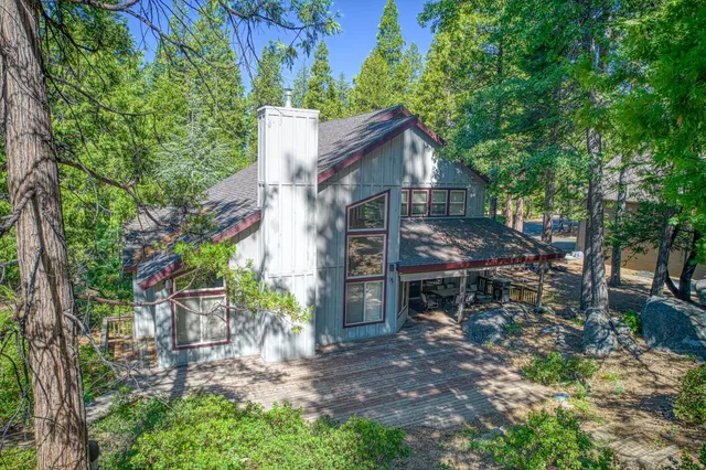 a view of a house with a yard and large trees