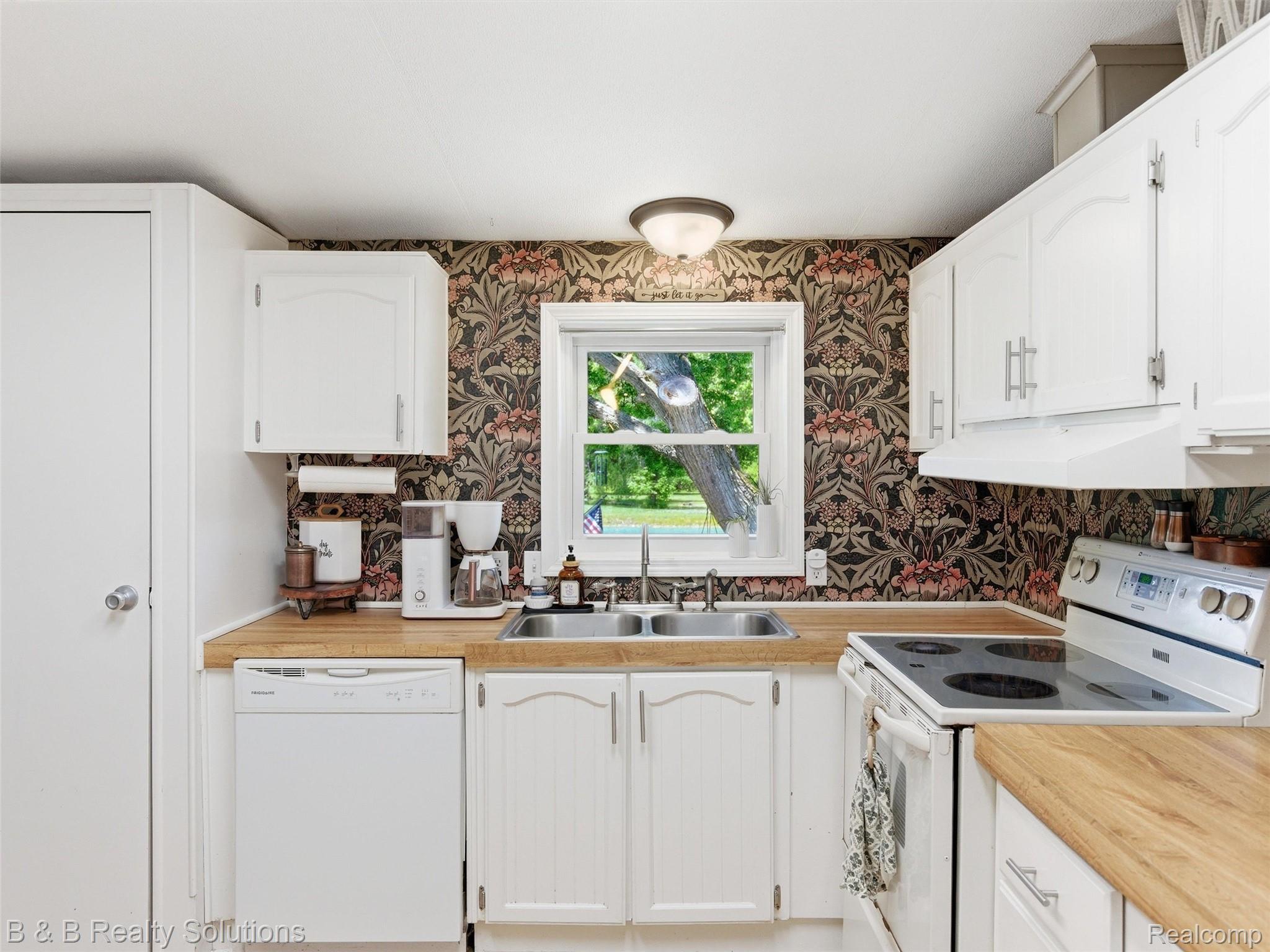 60455 Bates Road New Haven, MI 48048 - Photo 51 of 58 White kitchen with wood-finish countertops and decorative patterned wallpaper