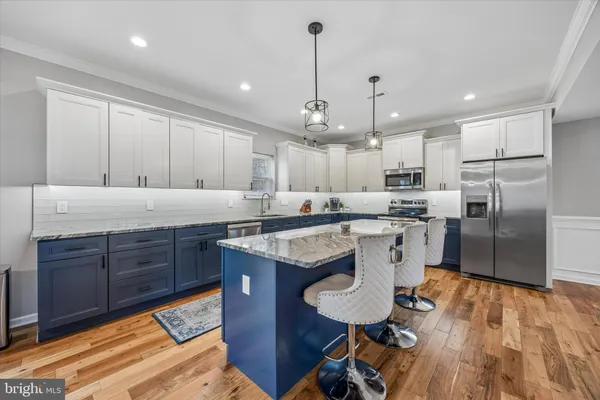 a kitchen with stainless steel appliances granite countertop a sink a stove a refrigerator and island with wooden floor