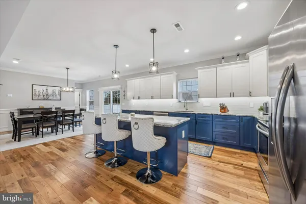 a kitchen with stainless steel appliances granite countertop a refrigerator a stove a sink dishwasher with a dining table and chairs with wooden floor