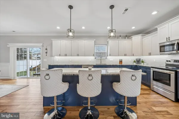 a kitchen with stainless steel appliances kitchen island granite countertop a dining table chairs and white cabinets