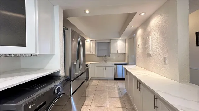 a large kitchen with a large counter top space appliances and cabinets