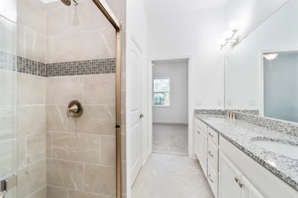 a bathroom with a granite countertop sink a mirror and a shower