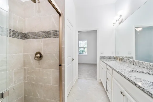 a bathroom with a granite countertop sink a mirror and a shower