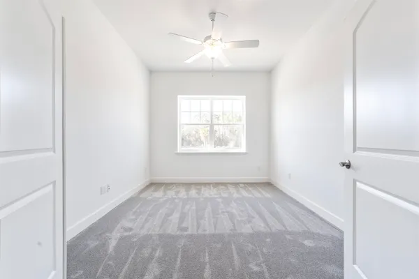 an empty room with windows and fan
