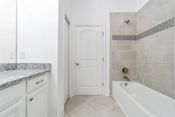 a bathroom with a granite countertop sink a mirror bathtub and shower
