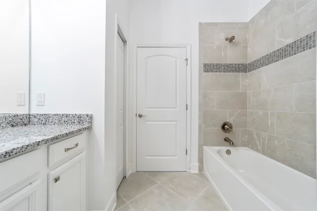 a bathroom with a granite countertop sink a mirror bathtub and shower