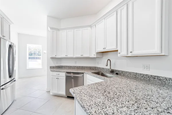 a kitchen with stainless steel appliances granite countertop a sink a stove a refrigerator and white cabinets with wooden floor