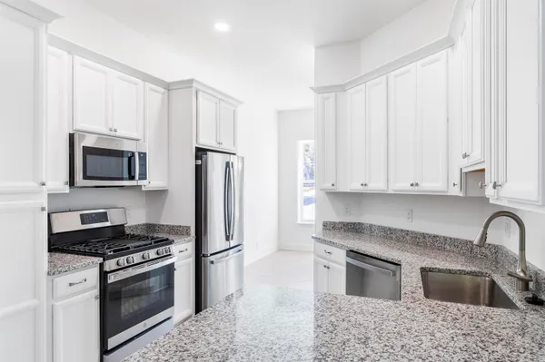 a kitchen with granite countertop a refrigerator stove and microwave