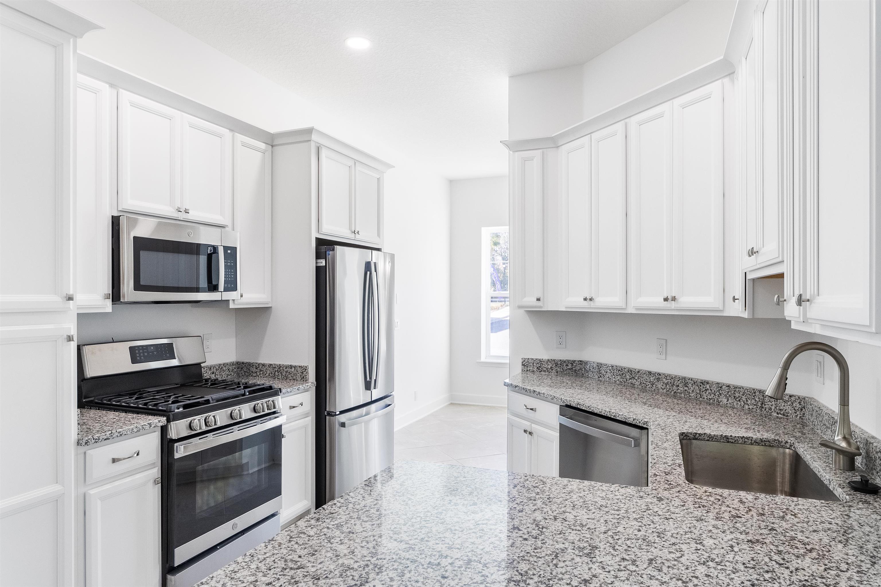 272 Grand Ravine Drive St. Augustine, FL 32086 - Photo 9 of 41 a kitchen with granite countertop a refrigerator stove and microwave
