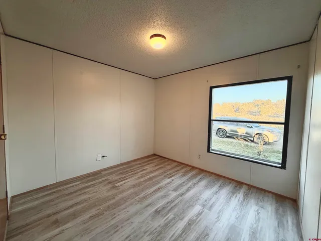 a view of an empty room with wooden floor and closet