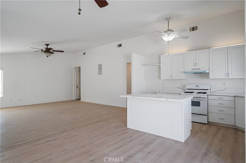 29582 Toomas Circle Menifee, CA 92587 - Photo 9 of 30 a kitchen with kitchen island white cabinets and stainless steel appliances