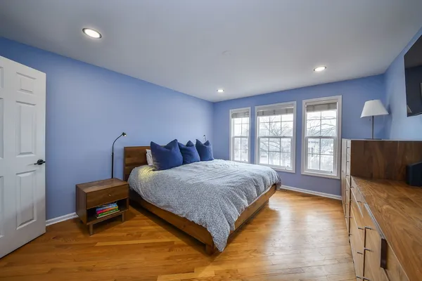 a spacious bedroom with a bed and wooden floor