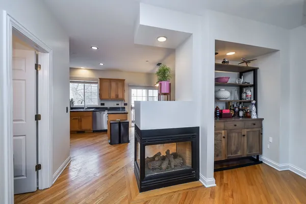 a living room with stainless steel appliances furniture a fireplace and a kitchen view