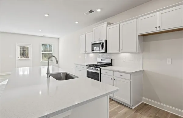 a kitchen with sink a microwave and cabinets