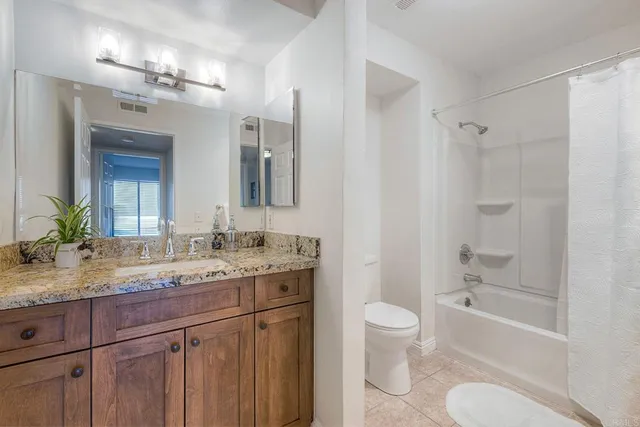 a bathroom with a granite countertop sink toilet a large mirror a bathtub and shower