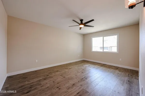a view of empty room with wooden floor and fan
