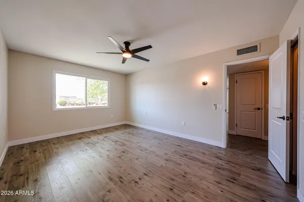 a view of an empty room with a window and wooden floor