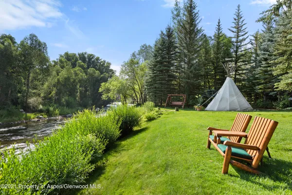 a view of a wooden chairs and fire pit in a yard