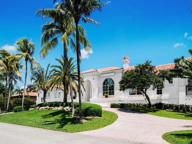 a front view of a house with a yard and palm trees
