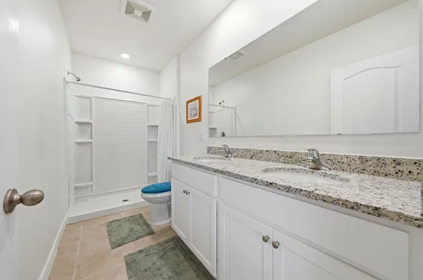 a bathroom with a granite countertop sink a toilet and shower