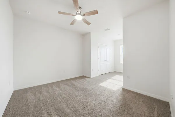 an empty room with a ceiling fan and a window