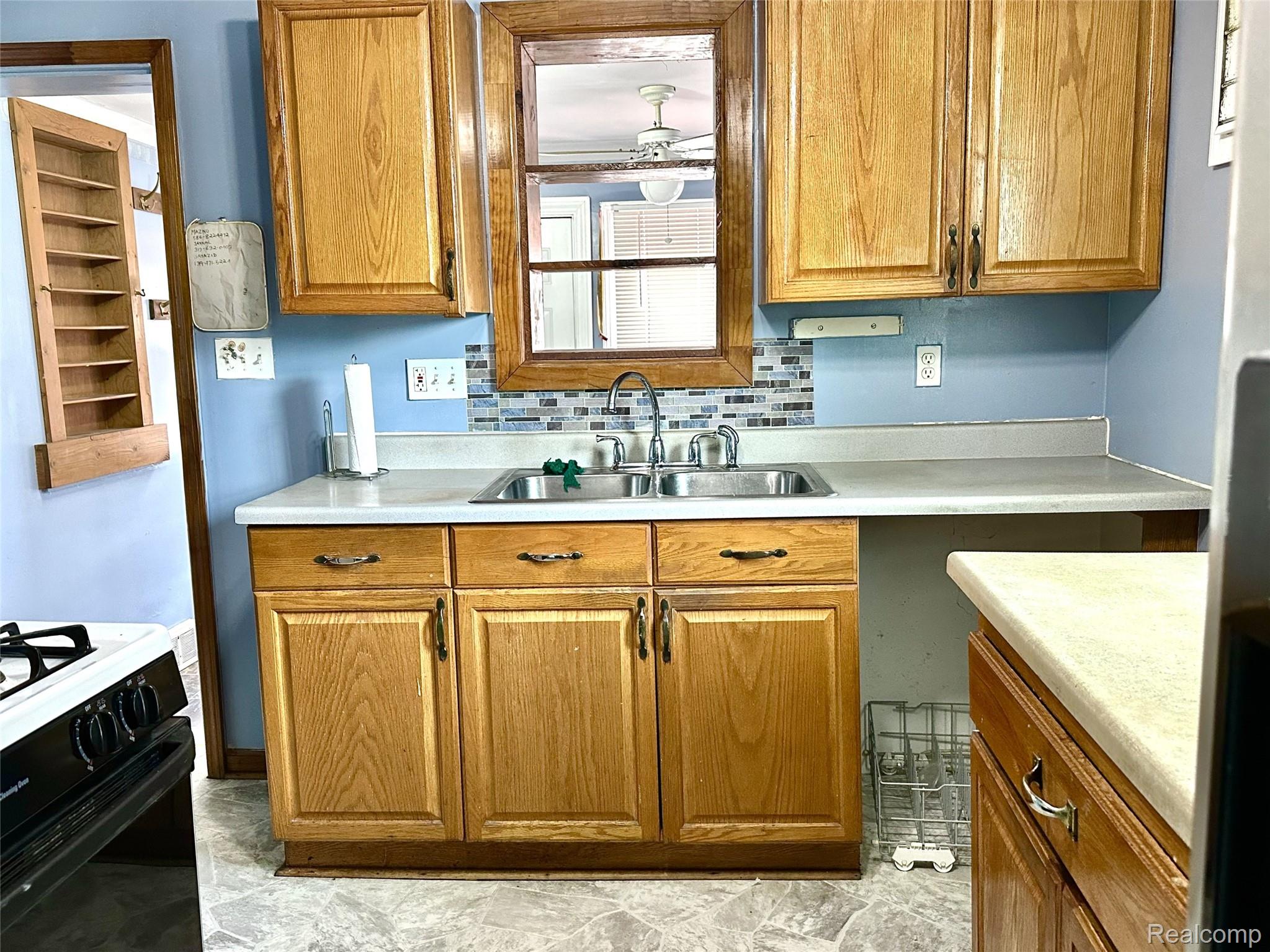 2135 Rome Avenue Warren, MI 48091 - Photo 15 of 25 Full kitchen featuring wood cabinetry, laminate countertops, stainless steel double basin sink, and mosaic tile backsplash