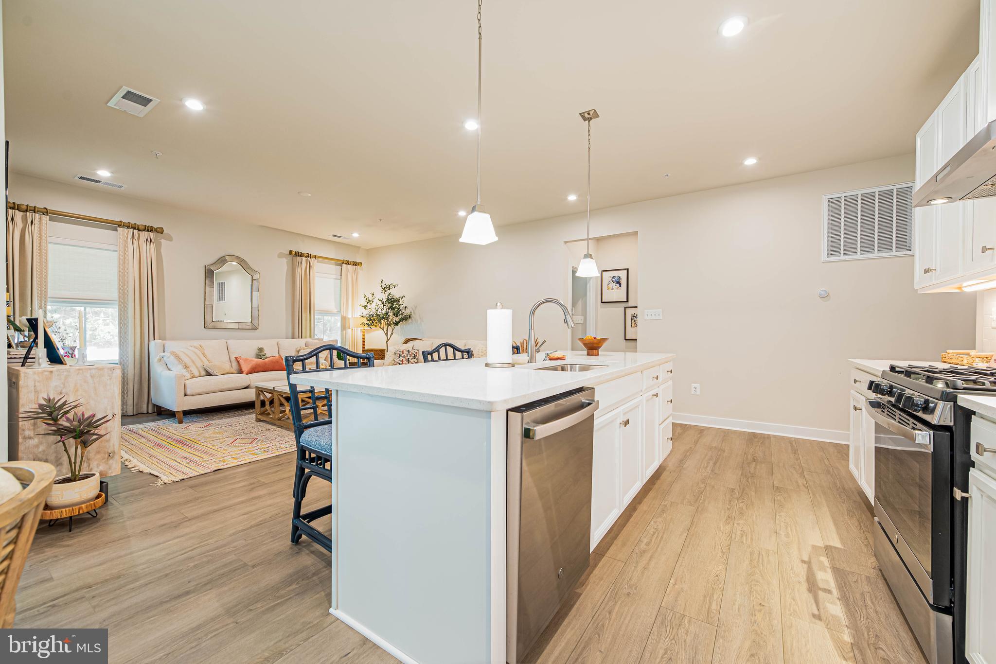 12115 Snug Harbor Road Berlin, MD 21811 - Photo 13 of 46 a large white kitchen with a stove a sink a refrigerator and a dining table with wooden floor