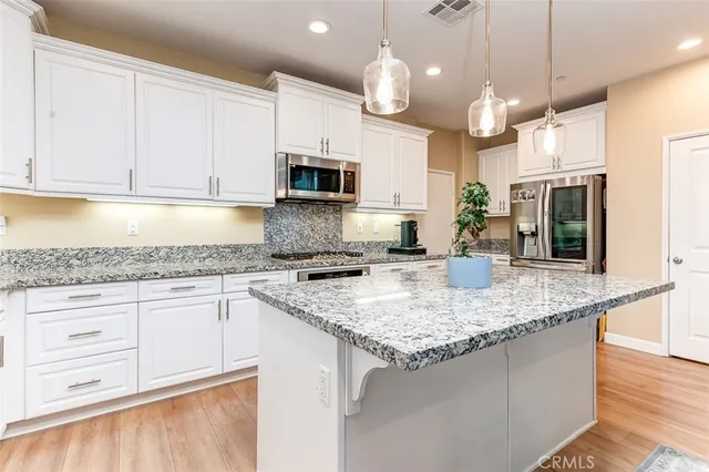 a kitchen with kitchen island granite countertop a sink a counter top space appliances and cabinets