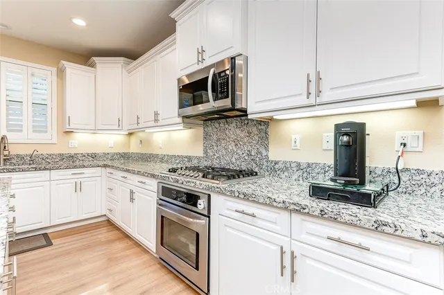 a kitchen with granite countertop white cabinets stainless steel appliances and a sink