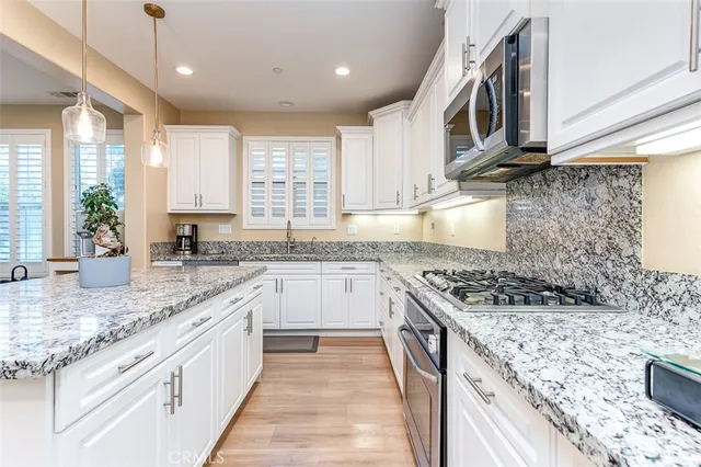 a kitchen with stainless steel appliances granite countertop a sink stove and cabinets