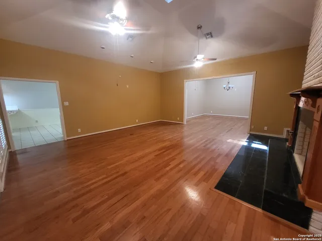 an empty room with wooden floor fireplace and windows