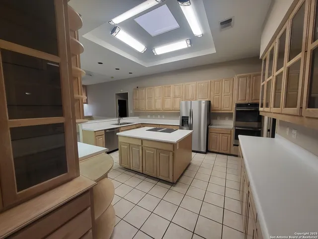 a kitchen with stainless steel appliances kitchen island granite countertop a refrigerator and a stove top oven