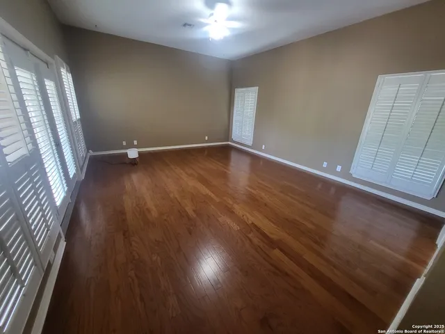 an empty room with wooden floor and windows
