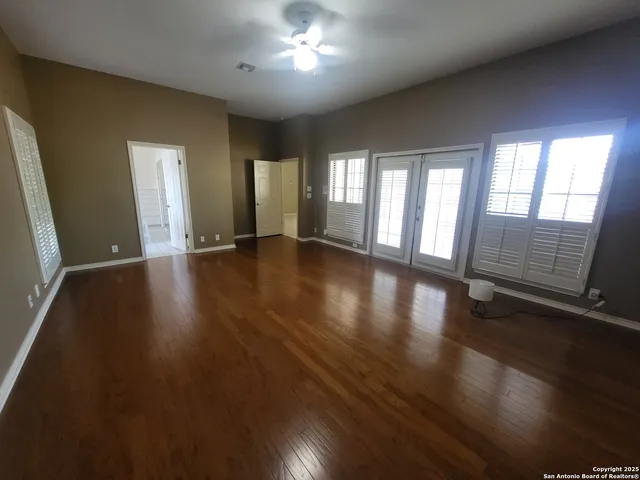 an empty room with wooden floor and windows