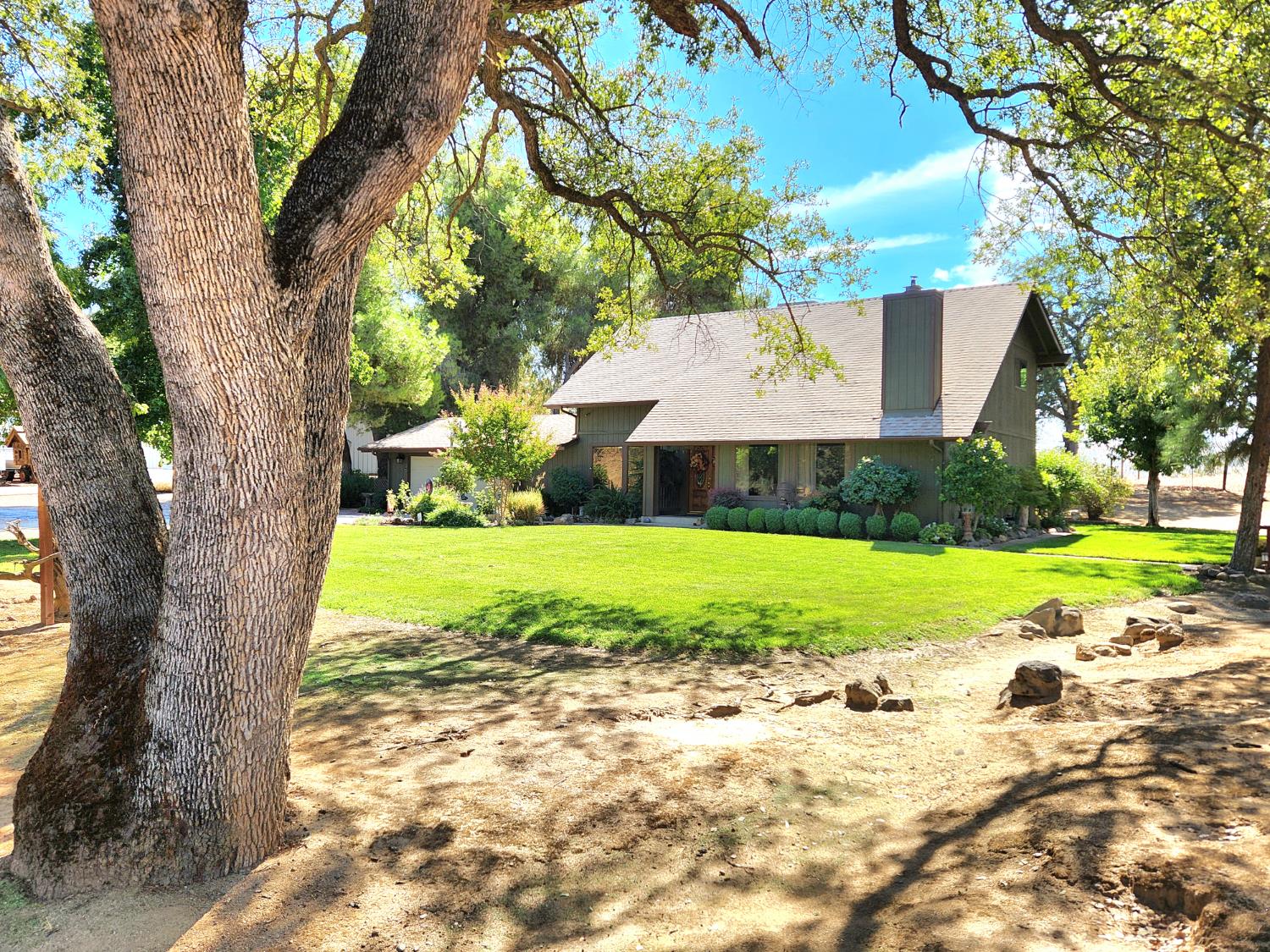a view of a house with a yard and large trees