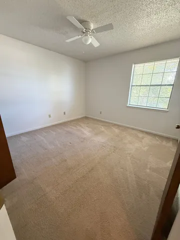 an empty room with windows and ceiling fan