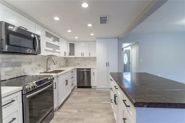 a kitchen with stainless steel appliances granite countertop a sink a stove and a microwave