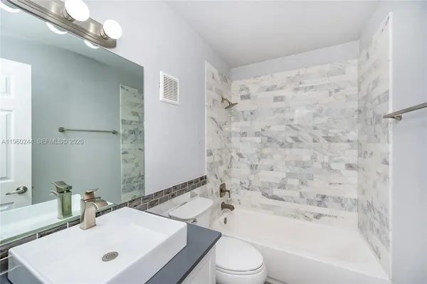 a bathroom with a bathtub shower sink vanity mirror and toilet
