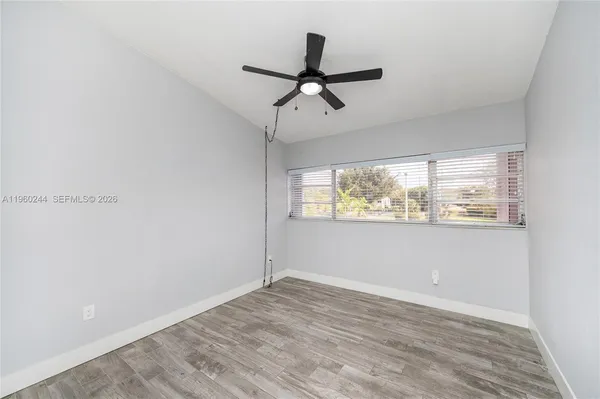 a view of empty room with wooden floor and fan