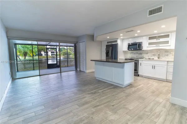 a large kitchen with stainless steel appliances granite countertop a stove top oven a sink with wooden floors and large cabinets