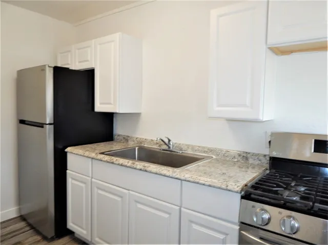 a kitchen with granite countertop a sink stove and refrigerator
