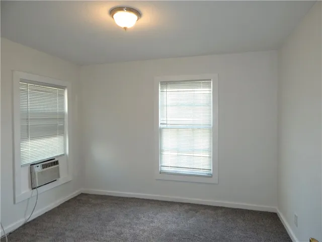 an empty room with a fireplace and windows