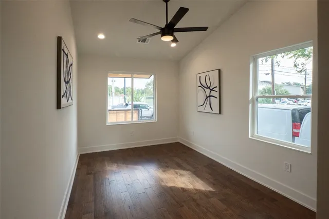 a view of an empty room with a window and wooden floor